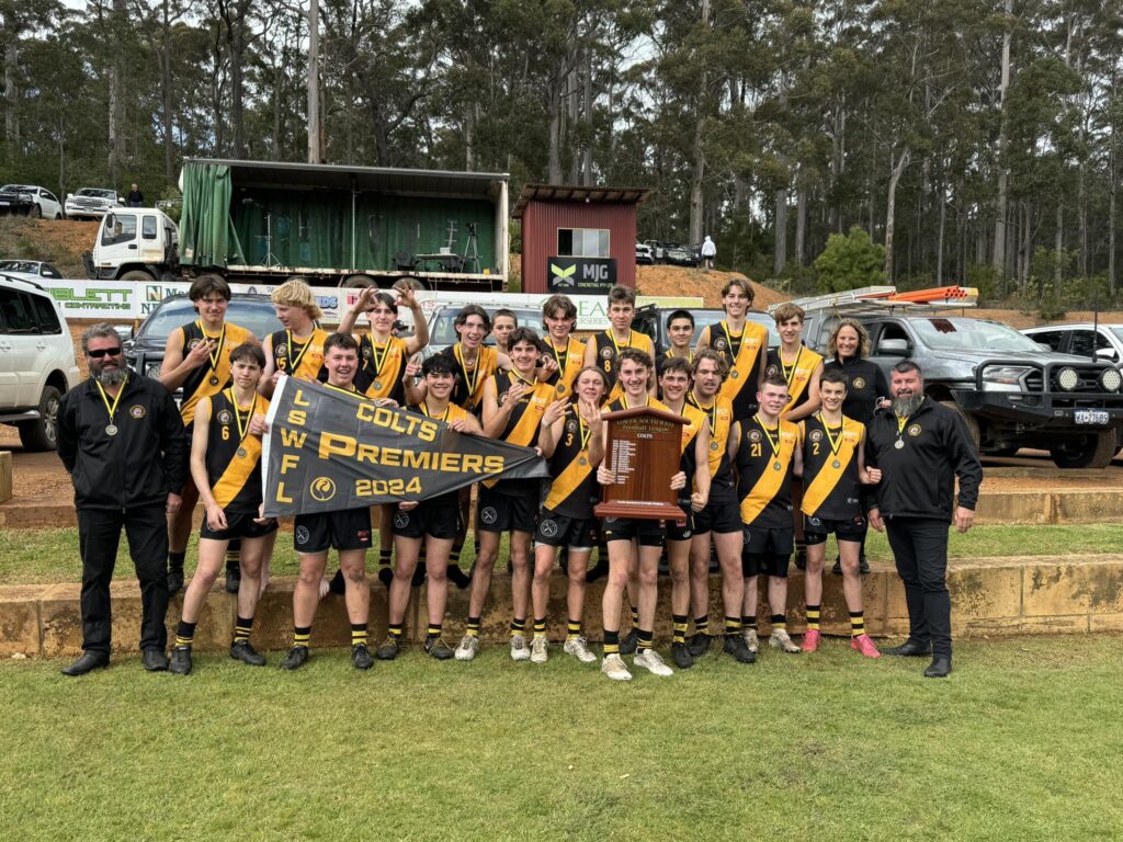 Manjimup Tigers players celebrate their 2024 LSWFL East Perth Football Club Colts Grand Final victory, lifting the premiership shield and flag.